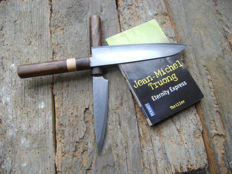 Planqué derière un santoku Orion. Lame en suminagashi 67 couches coeur en VG10 - Manche en noyer.